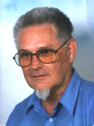 Photo of Klaus Daube: blue shirt, goat beard, large glasses with narrow border, hair with Navy cut